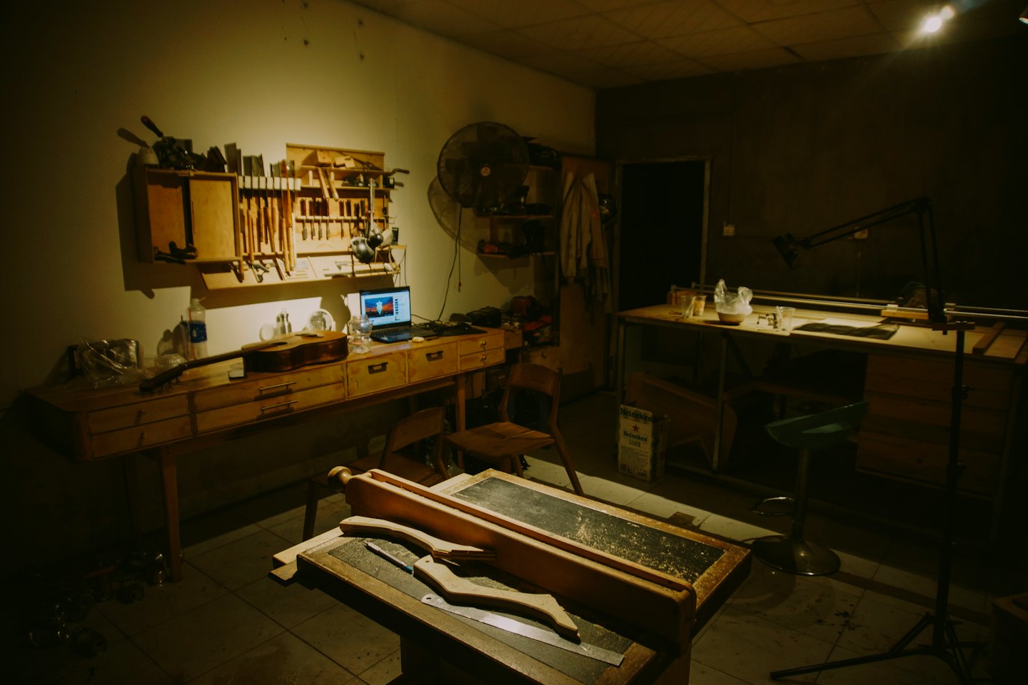 Acoustic guitar and laptop sit on a luthier's wooden workbench.