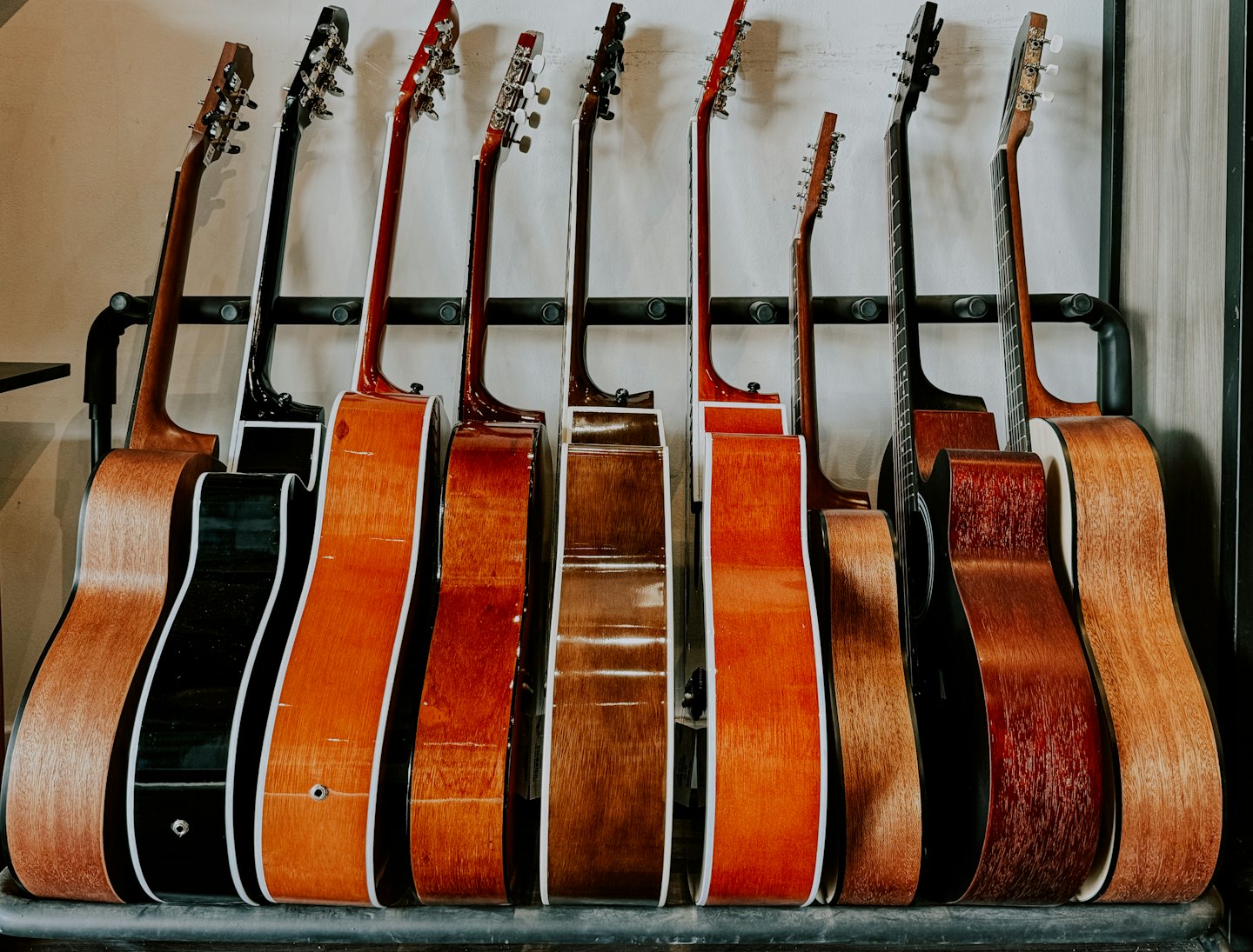 Several acoustic guitars rest in a display rack.